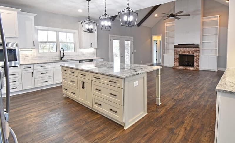 White shaker kitchen with a large island and a brick fireplace