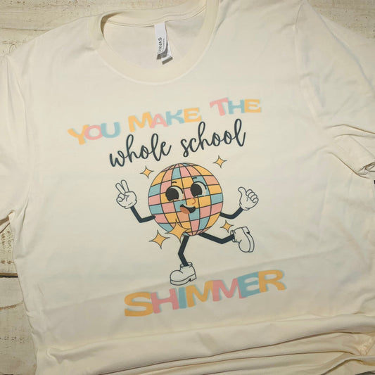 **Alt Text for "You Make The Whole School Shimmer" Teacher Shirt:**  "Teacher wearing a Bella-Canvas Natural shirt with a captivating message 'You Make The Whole School Shimmer.' The design symbolizes the teacher's dedication to education and creating a positive learning environment. The shirt exudes comfort and style, making it suitable for both classroom and casual wear."  Keywords: Teacher Shirt, Shirts for Teachers, Teacher Shirts