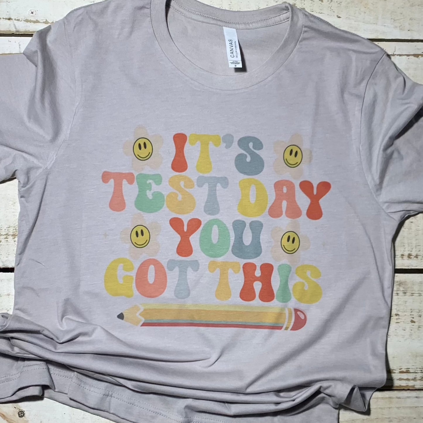 **Alt Text for "It's Test Day You Got This Teacher Shirt":**  A unisex Bell Canvas Silver shirt with the words "It's Test Day You Got This!" printed in bold, motivational letters. The design exudes positivity and is perfect for teachers looking to inspire confidence on test days. The shirt's comfortable fabric and vibrant print make it an ideal choice for educators of all ages.  Shirt for Teacher